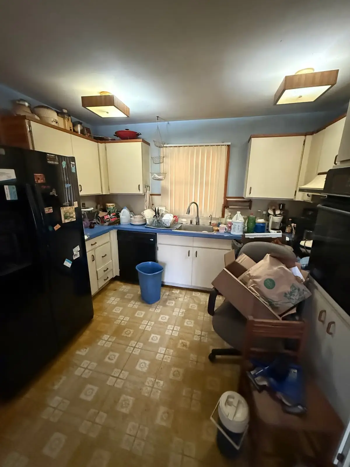 Selling a house during a divorce in Coram: kitchen with a black fridge and patterned vinyl floor