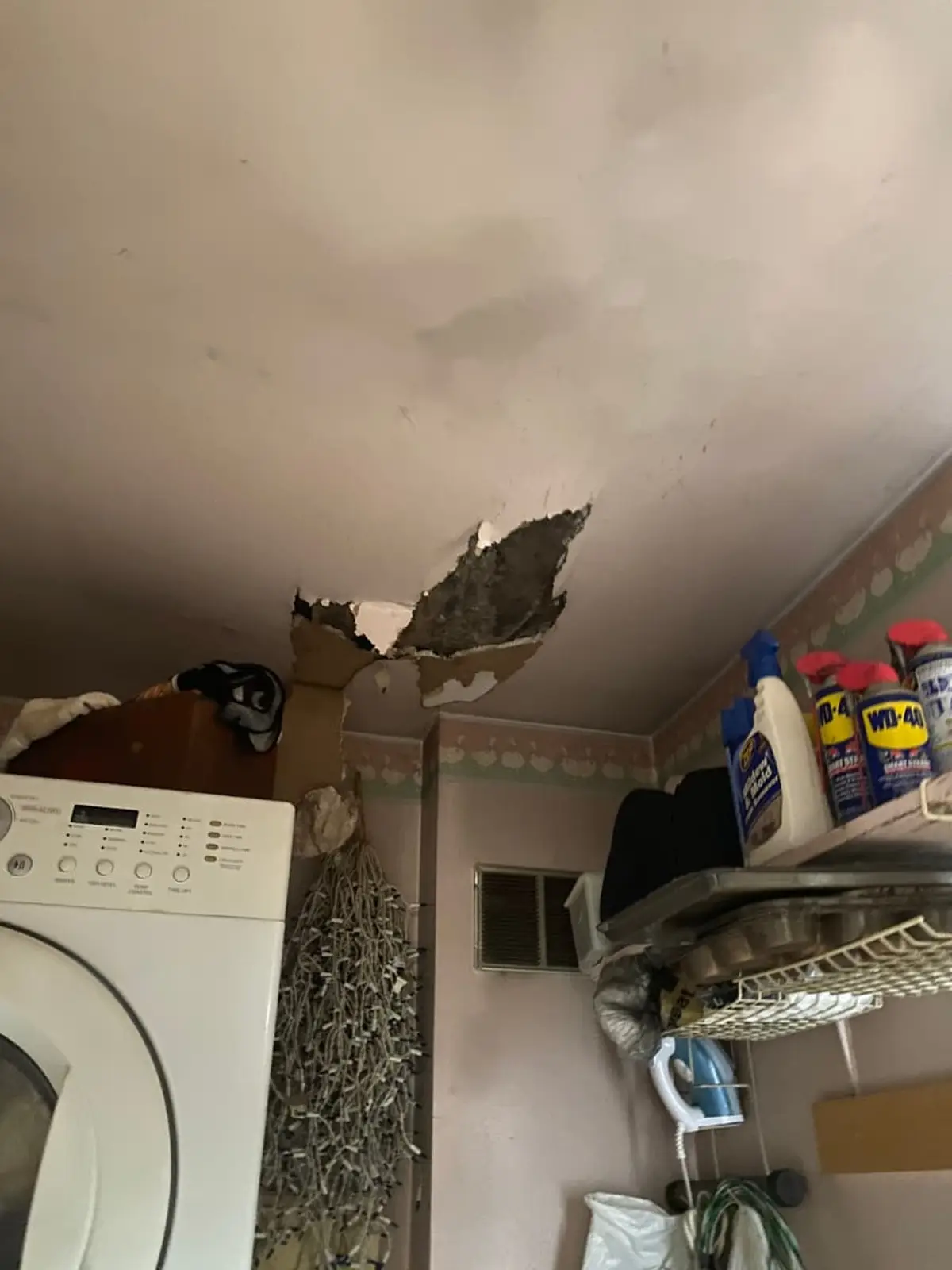 Selling a fire-damaged house in Coram: laundry room ceiling with a hole torn through drywall