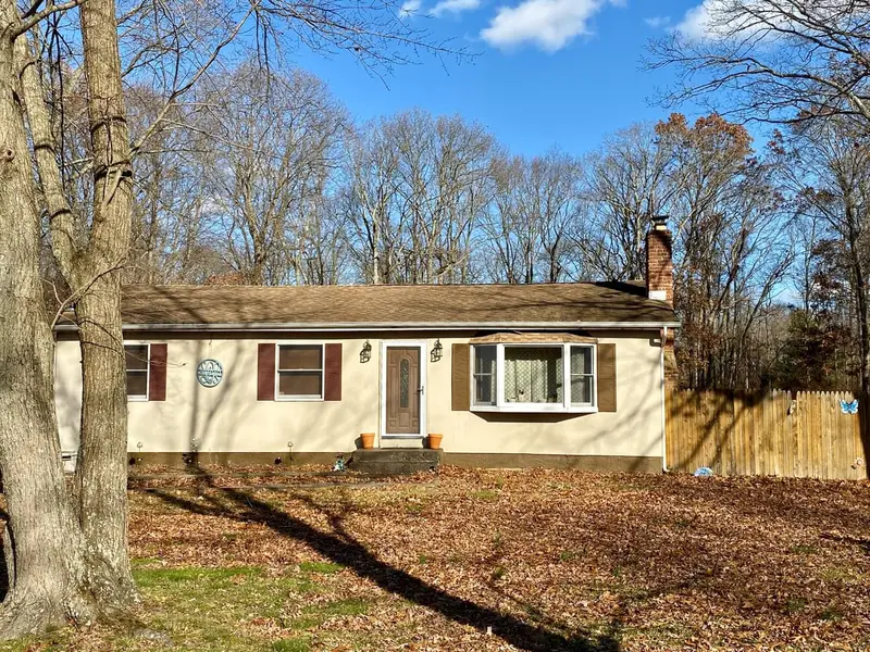 Ranch house with dark shutters and a leaf covered lawn, Coram, NY