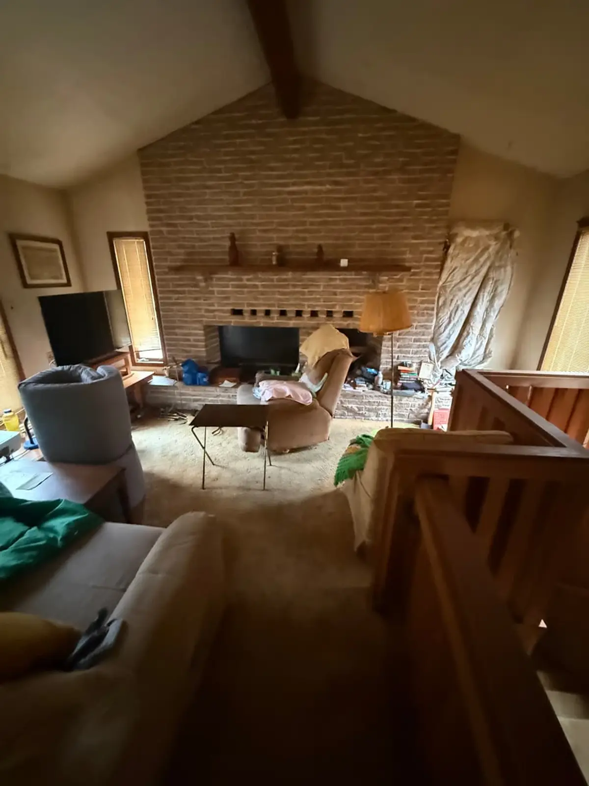 Selling a house with tenants in it in Coram: vaulted family room with a tall brick fireplace