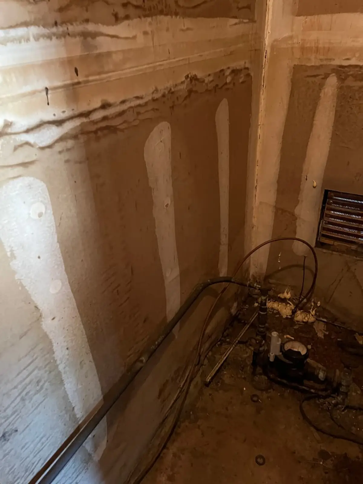 Selling a water-damaged house in Coram: water lines staining a basement wall above old pipes